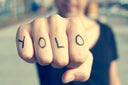 young man with the word yolo, for you only live once, tattooed in his hand, with a filter effect