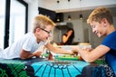 Two brothers laughing playing a board game on the kitchen table