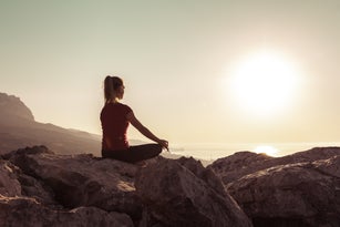 Young woman practices yoga and meditates on the mountain