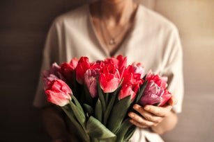 Portrait of beautiful woman with bouquet of spring flowers at home.