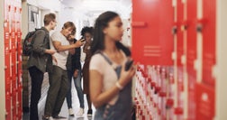 Shot of a teenage girl standing next to her locker and being bullied at high school