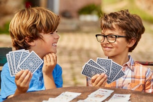 Smiling brothers playing cards at table in yard