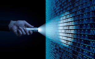 Man aiming flashlight at binary code