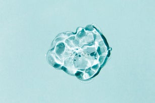 Transparent drop of Gel on blue background. Liquid hyaluronic acid gel. Flat lay, top view, copy space
