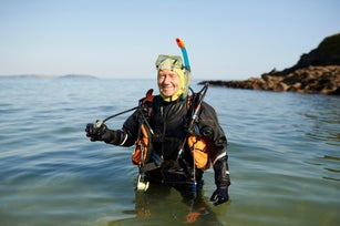 Portrait of senior scuba diver standing in sea with full diving kit.