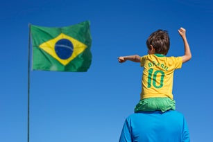 Boy and his father looking up at the Brazilian flag.
