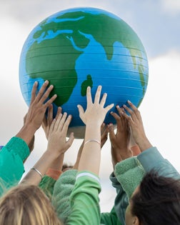 Group of teenagers holding up the world