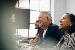 Cheerful male and female entrepreneurs talking in meeting at board room during pandemic