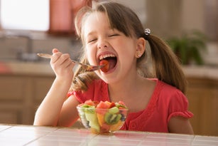 Hungry Caucasian girl eating fruit salad