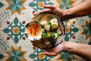 Vietnamese leaf vegetable paper rolls with stewed belly pork on floral pattern background