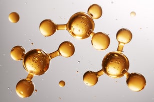 Golden molecules floating and connecting, representing innovation in cosmetics