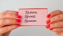 Female hands holds flashcards with handwritten irregular English verbs. Language learning concept