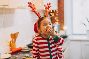 Child in red and white suit eats Christmas cookies