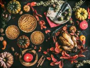 Thanksgiving day dinner table with pumpkin pie, roasted turkey and festive autumn decoration and candles
