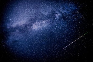 A meteor leaves a multicolored trail of light in the sky and crosses the Milky Way during the 2023 Perseid meteor shower