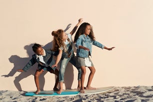 Girls playing on surfboard on the beach, on studio backdrop
