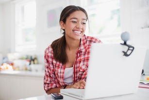 Smiling teenage girl enjoying video chat on laptop