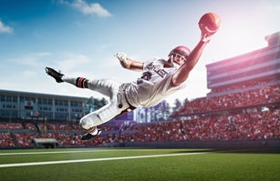 American football player catching ball mid air in stadium
