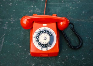 A red historical telephone with dial from the cold war period on an old table
