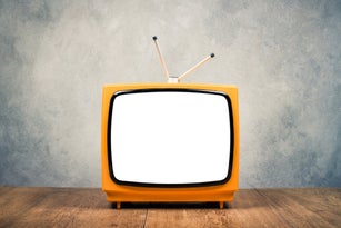 Retro old orange portable TV receiver frame on wooden table front textured grunge concrete wall background. Vintage instagram style filtered photo