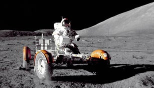 A U.S. astronaut driving a lunar vehicle on the surface of the Moon.