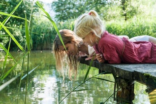 Mother and daughter lying on jetty at a lake looking at water