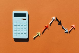 Blue calculator and a graph made from colored arrows. Brown background. Multi-colored lines in the graphics. Blue calculator.