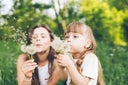 Mother and daughter having fun blowing dandelions