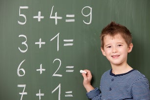 Schoolboy at blackboard with arithmetic problems