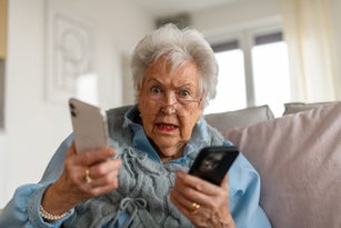 Confused senior woman holding two smartphones. Phone scams on elderly people.