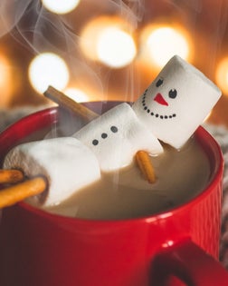 Red mug with hot chocolate with melted marshmallow snowman