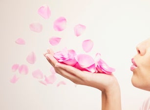 Woman blowing pink rose petals