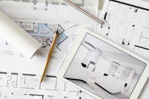 Architecturalblueprints and digital tablet displaying modern showcase interior