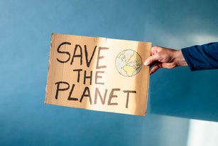 Man's hand holding a cardboard sign that says SAVE THE PLANET