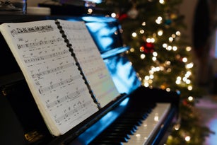 Sheet music on piano, Christmas tree in background