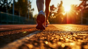 Slender Legs In Sneakers Of A Girl Running In The Rays Of The Rising Sun. Copy Space