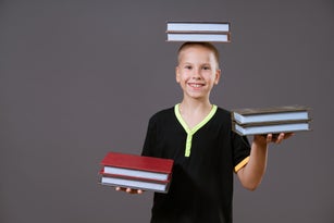 funny boy holding a book in his hands and on his head