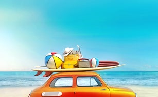 Small retro car with baggage, luggage and beach equipment on the roof, fully packed, ready for summer vacation, concept of a road trip with family and friends, dream destination, very vivid colors with dominant blue sky and ocean and bright orange car.