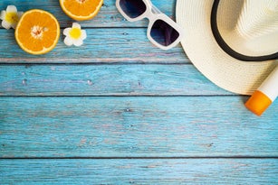 Beautiful summer holiday, Beach accessories, ornage, sunglasses, hat and sunblock on wooden backgrounds