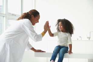 Doctor and girl high-fiving in office