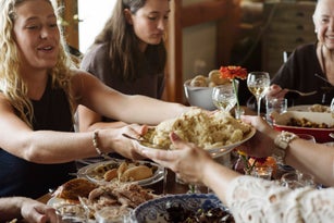 Women passing food while sitting at dining table during Thanksgiving