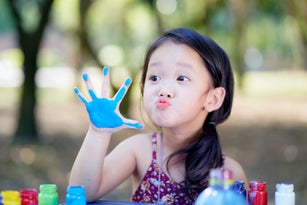 Happy little child painting water color with her hand. smiley little child girl with painted hand.