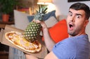 Funny man holding pineapple and pizza