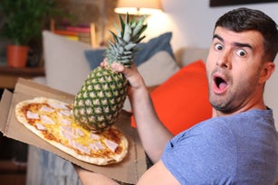 Funny man holding pineapple and pizza