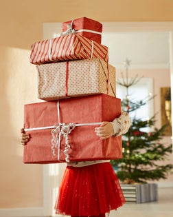 Girl holding tall stack of christmas presents