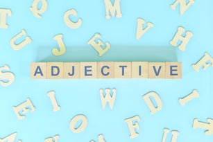 Adjective or adjectives concept in English grammar and learning class lesson. Wooden blocks typography word flat lay in blue background.