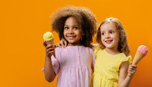 Two girlfriends in anticipation of a sweet treat, holding ice cream in their hands on a hot summer day.