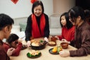 Joyful three generations Asian family having reunion dinner together in dining room and celebrating Chinese New Year at home.