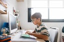 Boy using computer keyboard for e-learning at home