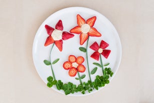 Strawberries in shape of flowers in white plate from above